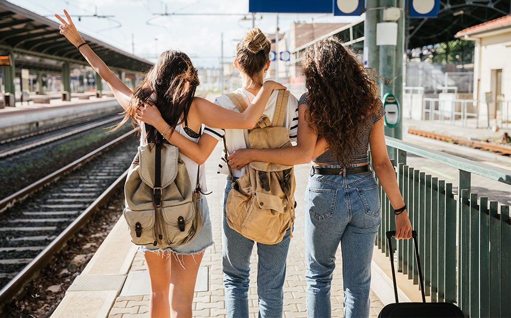 3 amis attendent le train sur le quai dans la bonne humeur